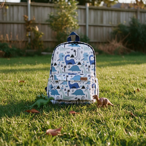 Kinderrucksack Dinolino auf der Wiese im Abendlicht